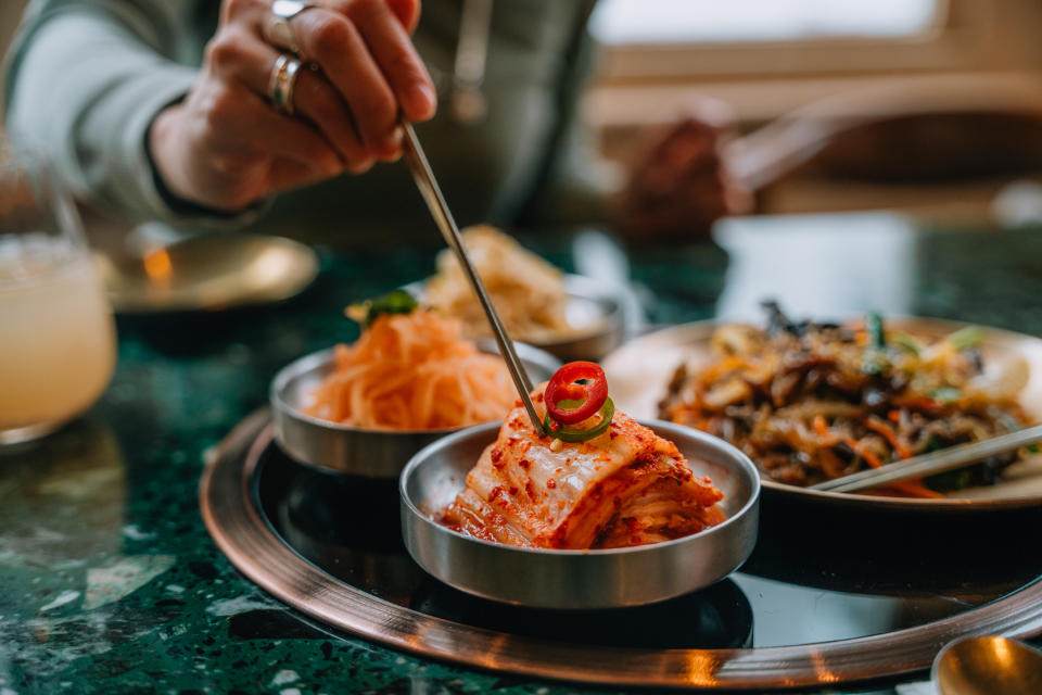 A woman enjoys Korean fermented vegetables (Banchan) with chopsticks. Korean food and culture.